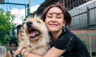 A woman holding a long-haired dog at the shelter and wondering, do you have to pay to adopt a dog?