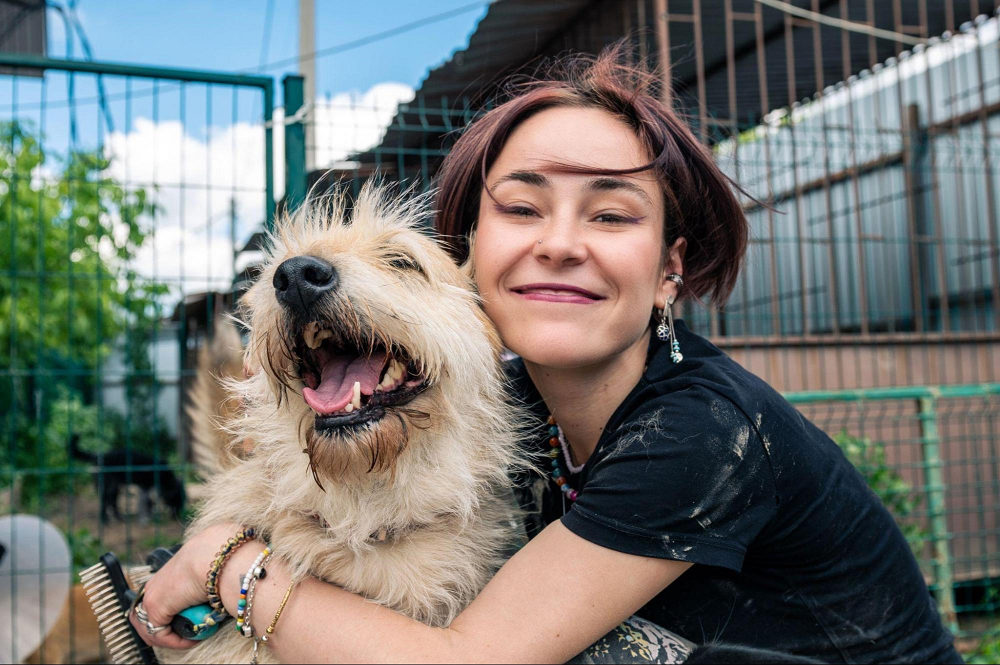 A woman holding a long-haired dog at the shelter and wondering, do you have to pay to adopt a dog?